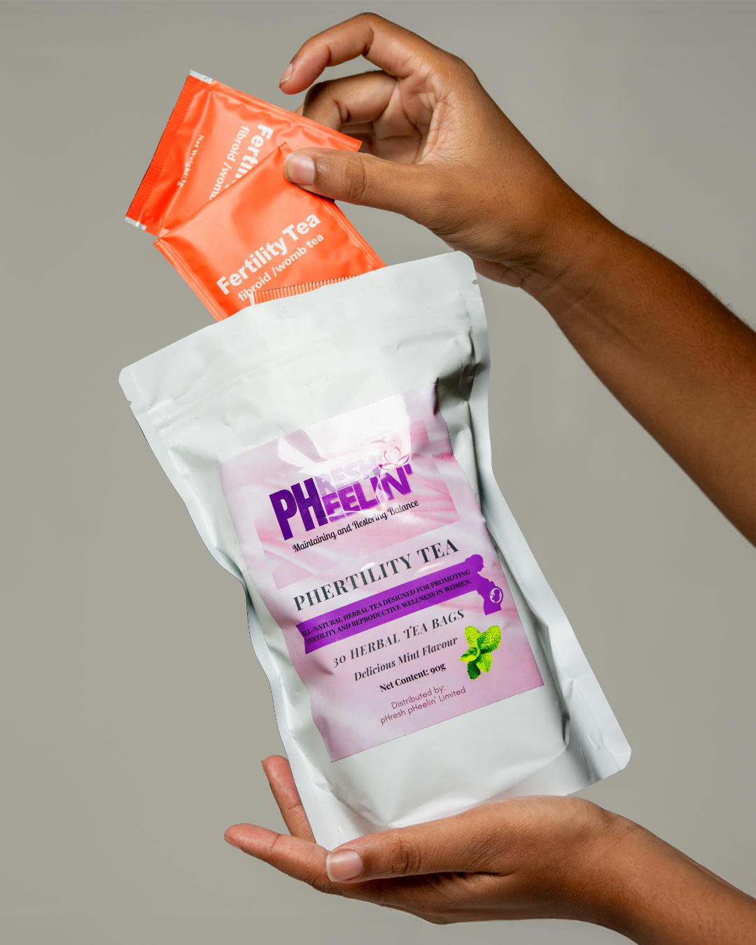 Hand holding a package of pHresh pHeelin' pHertility Tea against a neutral background